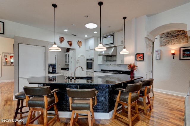 3102 N Springwater Ct N, Port Orange, FL 32128 - kitchen featuring oven, wall chimney exhaust hood, light wood-style flooring, a breakfast bar, and recessed lighting