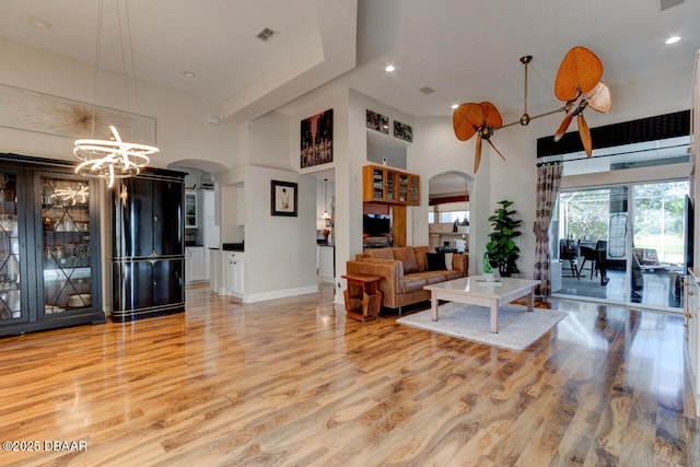 3102 N Springwater Ct N, Port Orange, FL 32128 - living area with arched walkways, light wood-style floors, a high ceiling, recessed lighting, and a chandelier
