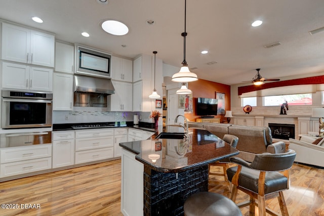 3102 N Springwater Ct N, Port Orange, FL 32128 - kitchen featuring stainless steel oven, a warming drawer, dark countertops, light wood-style floors, and recessed lighting