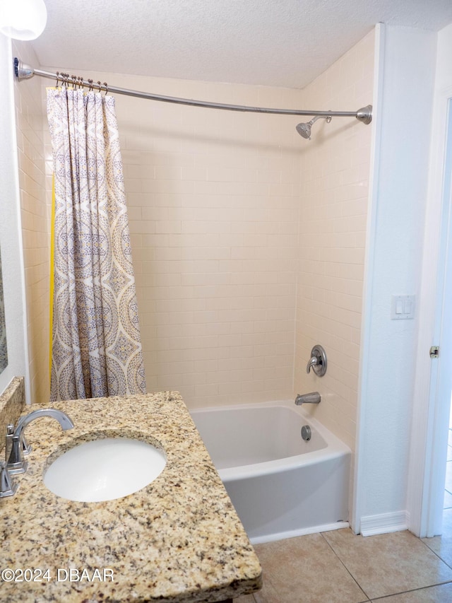 bathroom featuring tile patterned flooring, shower / bath combination with curtain, sink, and a textured ceiling