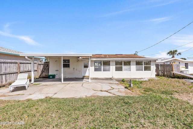 rear view of property featuring a yard, a patio area, fence, and stucco siding