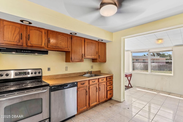 kitchen featuring stainless steel appliances, brown cabinets, a sink, and under cabinet range hood