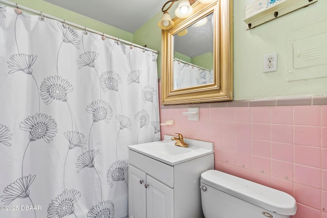 bathroom featuring toilet, tile walls, and vanity