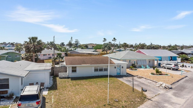 ranch-style home with a residential view, fence, driveway, and a front yard