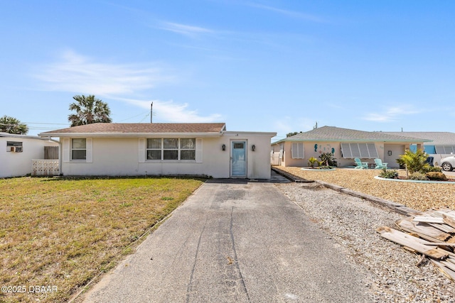 ranch-style home with a front yard and stucco siding