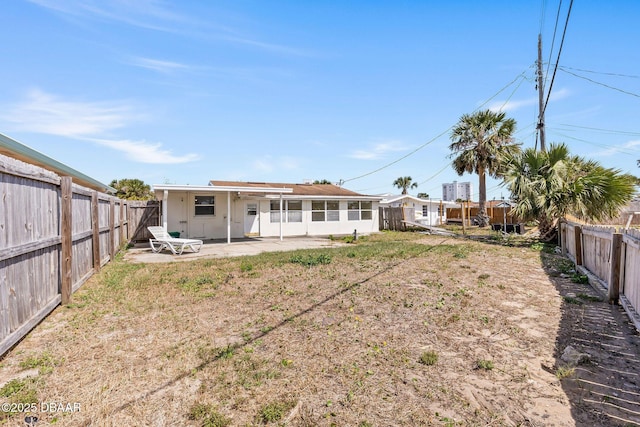 rear view of house with a fenced backyard and a patio