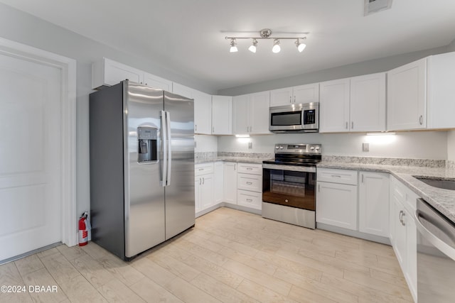 kitchen featuring light stone countertops, light wood-type flooring, white cabinetry, and stainless steel appliances