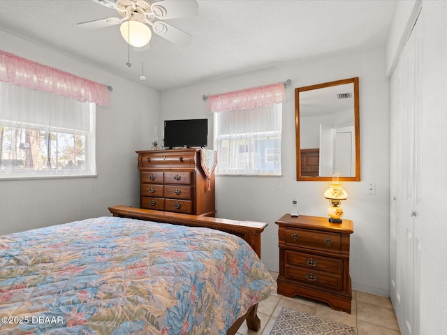 bedroom with ceiling fan, light tile patterned floors, and a closet