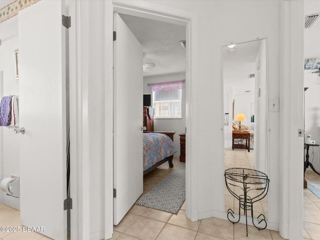 corridor featuring a textured ceiling and light tile patterned floors