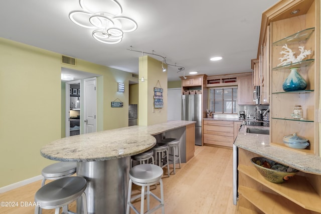 kitchen featuring sink, light stone counters, light wood-type flooring, and stainless steel appliances