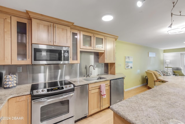 kitchen with sink, light stone countertops, light brown cabinetry, decorative light fixtures, and stainless steel appliances