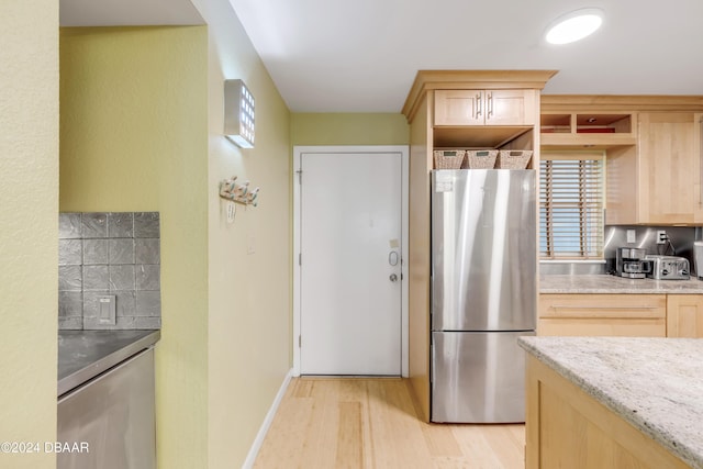 kitchen with light brown cabinets, light hardwood / wood-style flooring, stainless steel refrigerator, and a wealth of natural light