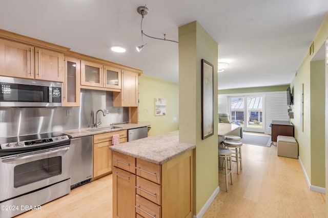 kitchen with light stone counters, sink, light wood-type flooring, and appliances with stainless steel finishes