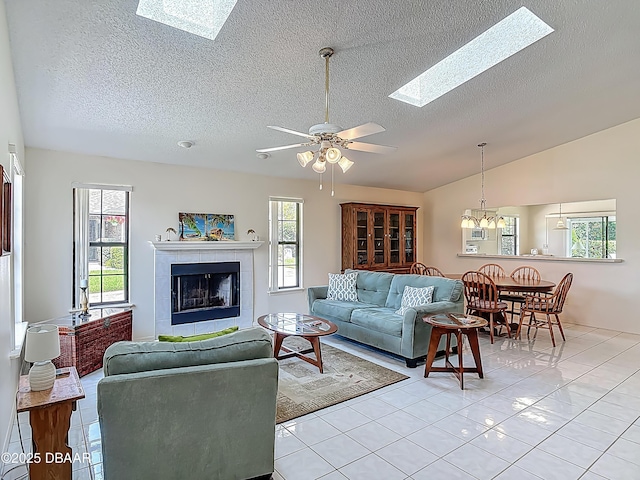 907 Silverleaf Pl, Port Orange, FL 32127 - living room with a textured ceiling, light tile patterned flooring, ceiling fan with notable chandelier, a fireplace, and vaulted ceiling with skylight