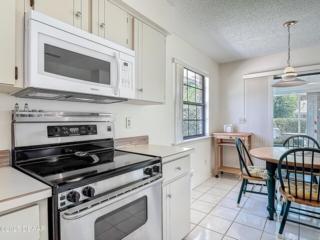 907 Silverleaf Pl, Port Orange, FL 32127 - kitchen featuring decorative light fixtures, light tile patterned floors, white microwave, stainless steel range with electric cooktop, and light countertops