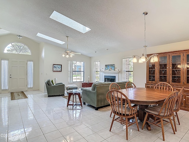 907 Silverleaf Pl, Port Orange, FL 32127 - dining space featuring a fireplace, light tile patterned flooring, a textured ceiling, and vaulted ceiling with skylight