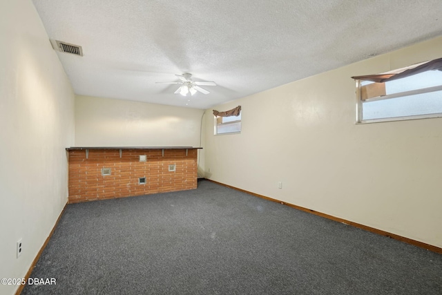 carpeted empty room with visible vents, baseboards, a textured ceiling, and ceiling fan