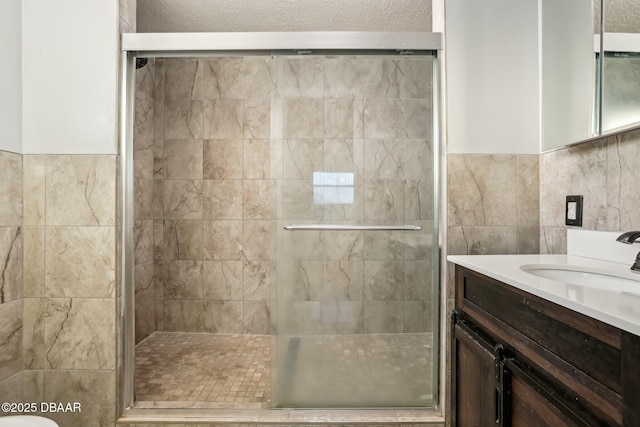 bathroom with vanity, tile walls, and a shower stall