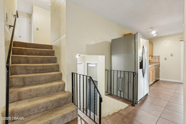 stairway featuring tile patterned flooring and vaulted ceiling