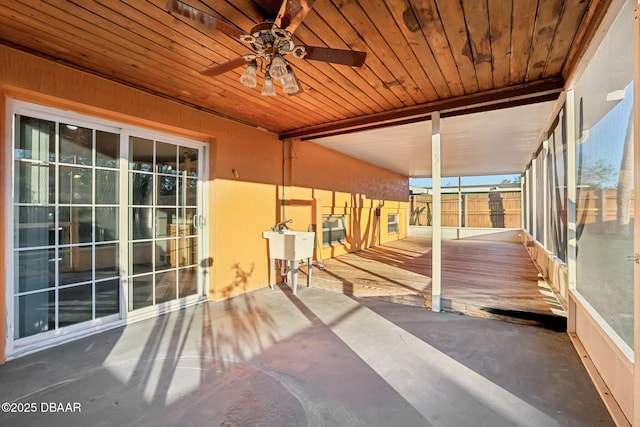 unfurnished sunroom featuring wooden ceiling, a ceiling fan, and a sink