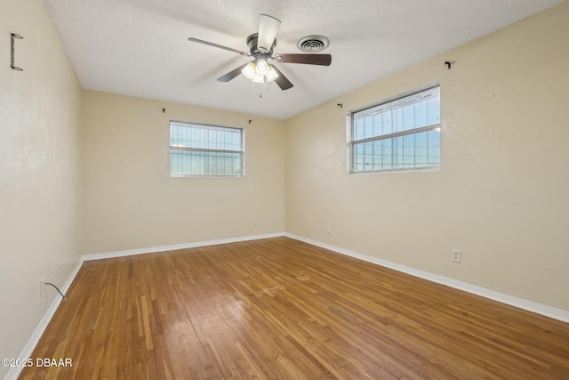 spare room featuring visible vents, ceiling fan, baseboards, a textured ceiling, and wood-type flooring