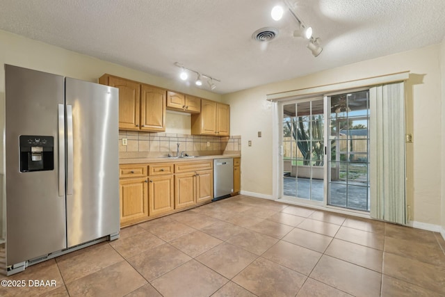 kitchen with visible vents, a sink, appliances with stainless steel finishes, light countertops, and decorative backsplash