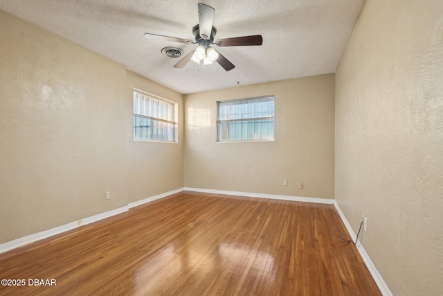 spare room with baseboards, visible vents, ceiling fan, hardwood / wood-style flooring, and a textured ceiling