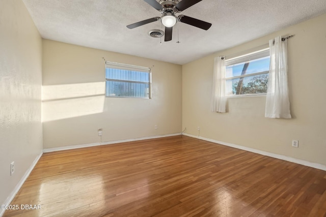 unfurnished room featuring hardwood / wood-style floors, a ceiling fan, visible vents, and a textured ceiling