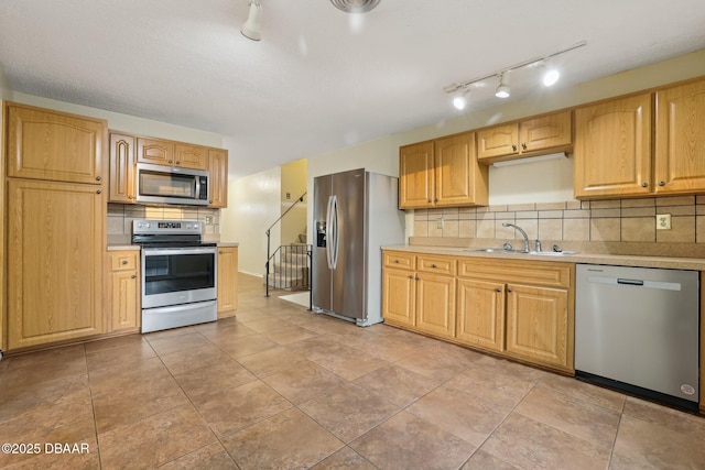 kitchen featuring a sink, stainless steel appliances, tasteful backsplash, and light countertops