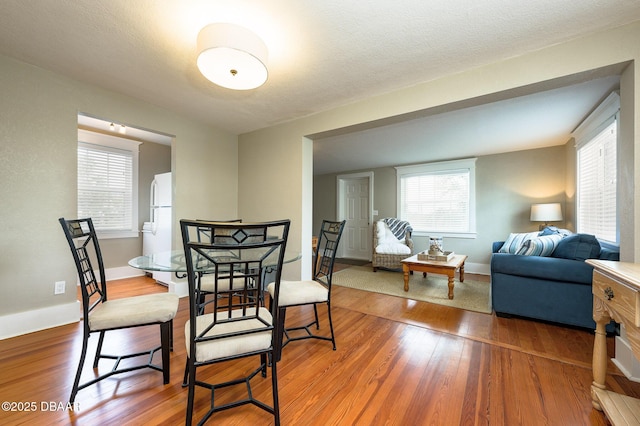 dining room with hardwood / wood-style flooring, a textured ceiling, and a healthy amount of sunlight