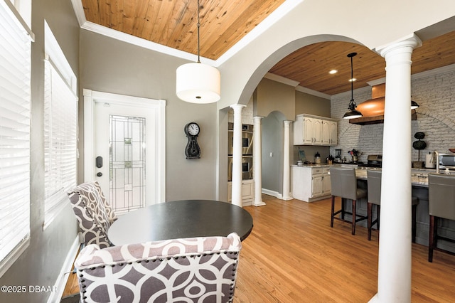 dining room with light hardwood / wood-style floors, wooden ceiling, crown molding, and ornate columns