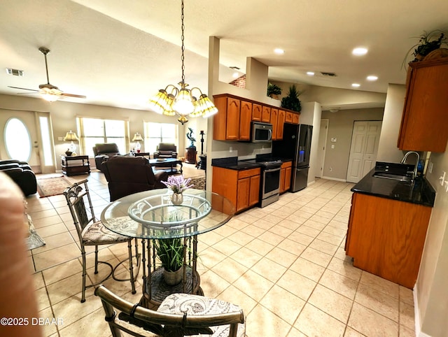 kitchen with stainless steel appliances, dark countertops, visible vents, open floor plan, and a sink