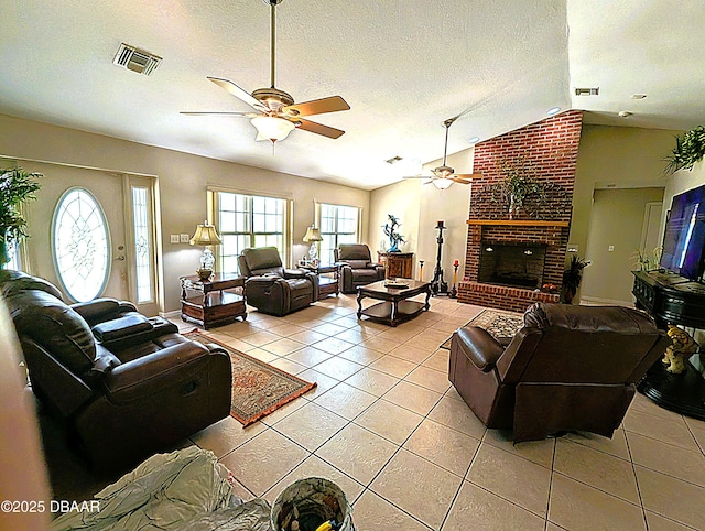 living area with light tile patterned floors, a textured ceiling, a fireplace, visible vents, and vaulted ceiling