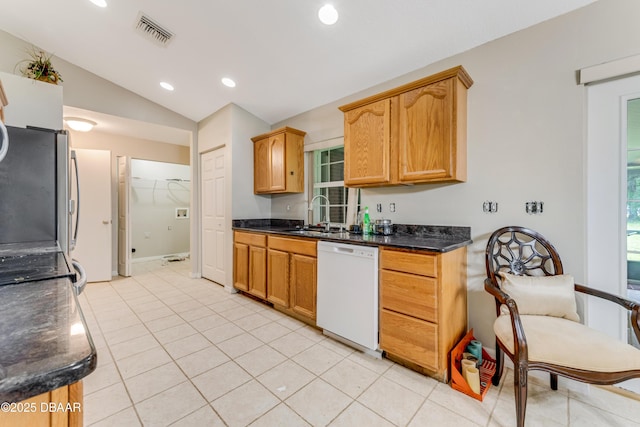 kitchen featuring lofted ceiling, a sink, visible vents, dishwasher, and dark stone countertops