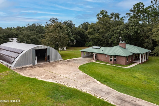 view of front of house featuring an outbuilding, concrete driveway, a front lawn, and brick siding