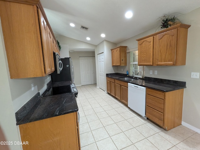 kitchen featuring vaulted ceiling, brown cabinetry, white dishwasher, and a sink