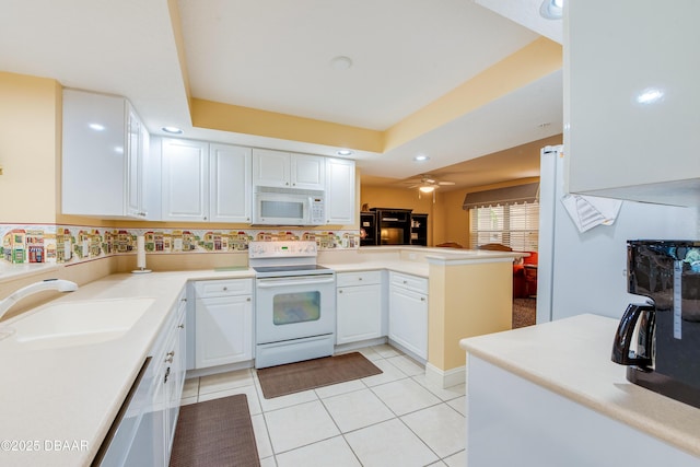 kitchen with kitchen peninsula, white appliances, sink, light tile patterned floors, and white cabinetry