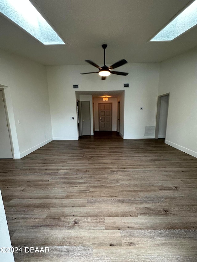 unfurnished living room featuring hardwood / wood-style floors, ceiling fan, and a skylight