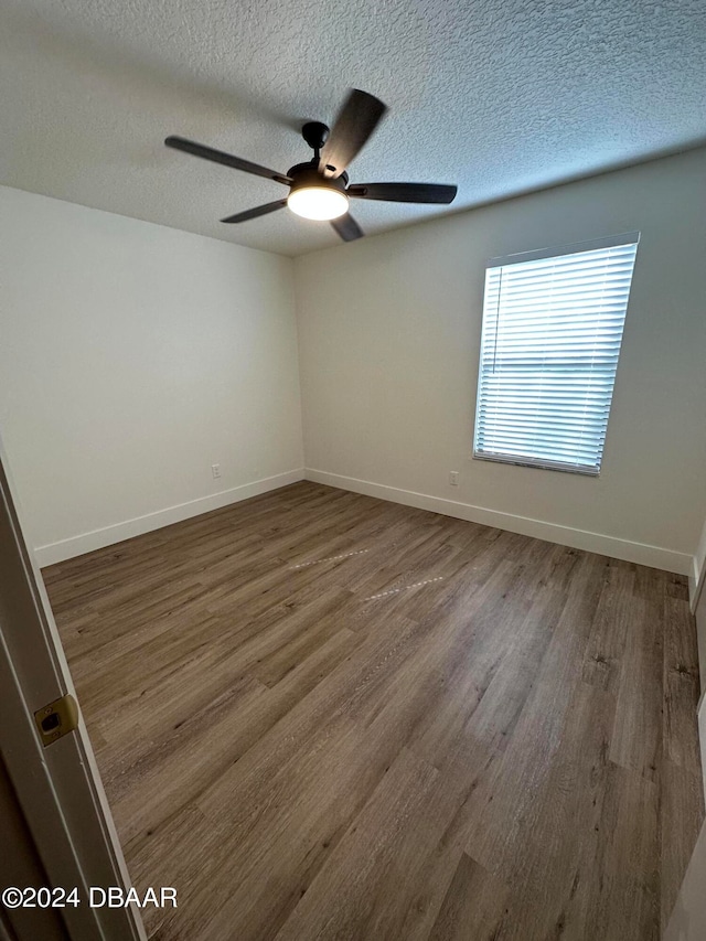 unfurnished room featuring ceiling fan, a textured ceiling, and dark hardwood / wood-style floors