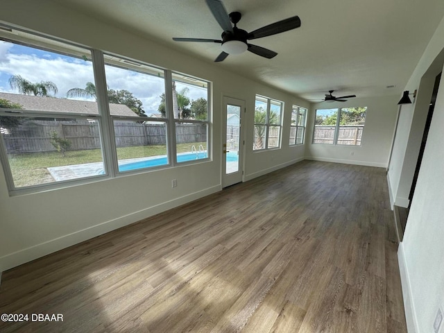 unfurnished sunroom with ceiling fan