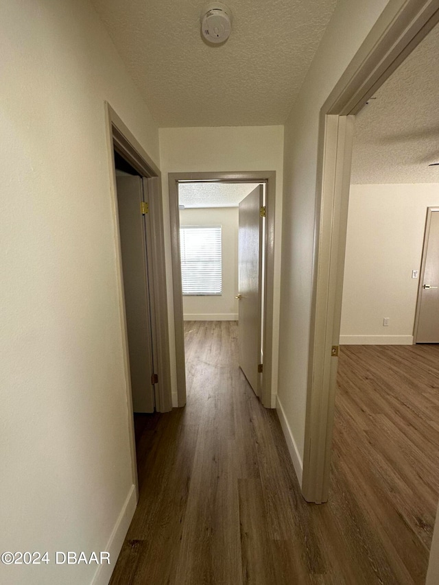 corridor with dark wood-type flooring and a textured ceiling