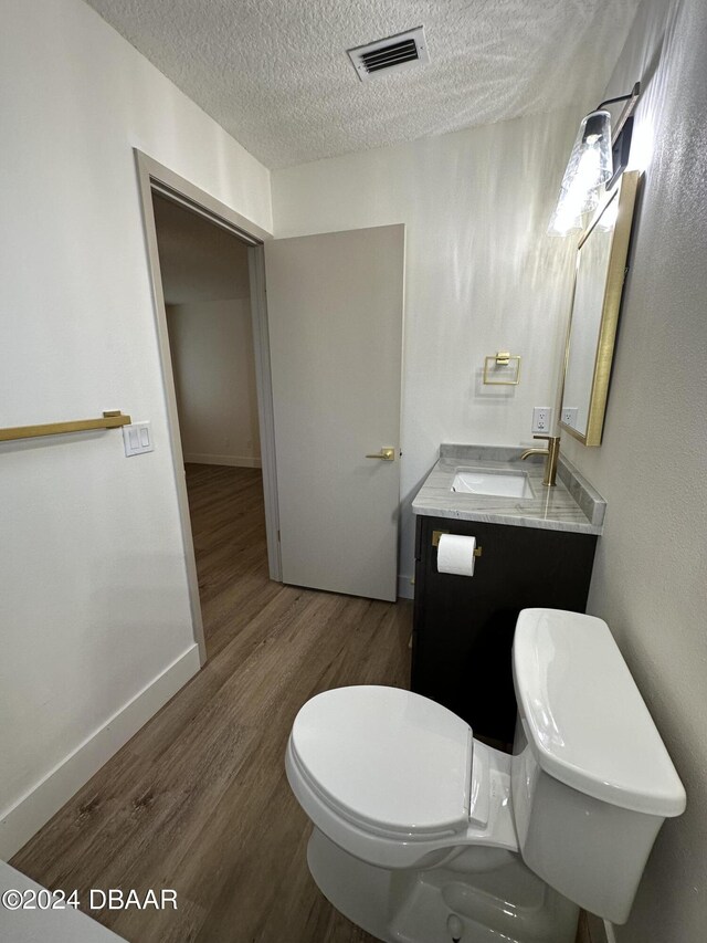 1824 Sabal Palm Dr, Edgewater, FL 32132 - half bathroom featuring a textured ceiling, toilet, wood finished floors, baseboards, and vanity