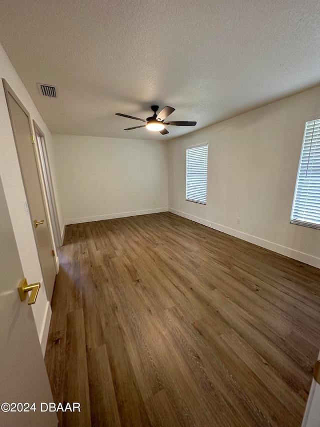 spare room featuring dark wood-type flooring, a textured ceiling, and ceiling fan