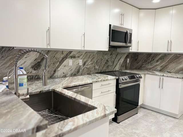 kitchen with sink, light stone counters, appliances with stainless steel finishes, tasteful backsplash, and white cabinets