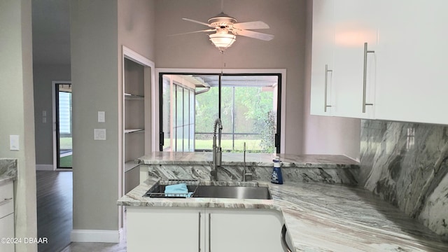 kitchen featuring white cabinetry, light wood-type flooring, light stone countertops, sink, and ceiling fan