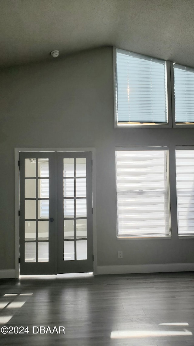 doorway to outside with a towering ceiling, a textured ceiling, dark hardwood / wood-style floors, and french doors