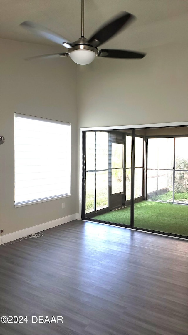 spare room featuring a towering ceiling, hardwood / wood-style floors, plenty of natural light, and ceiling fan