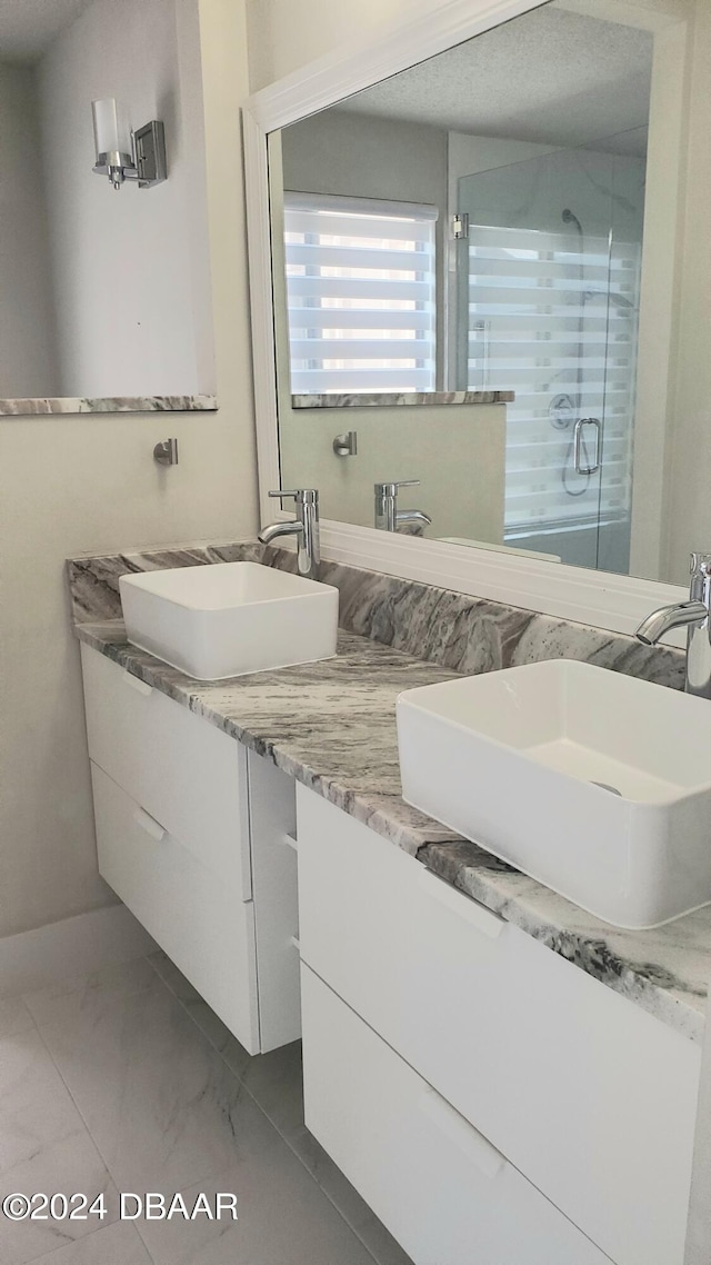 bathroom with a shower with door, vanity, and a textured ceiling