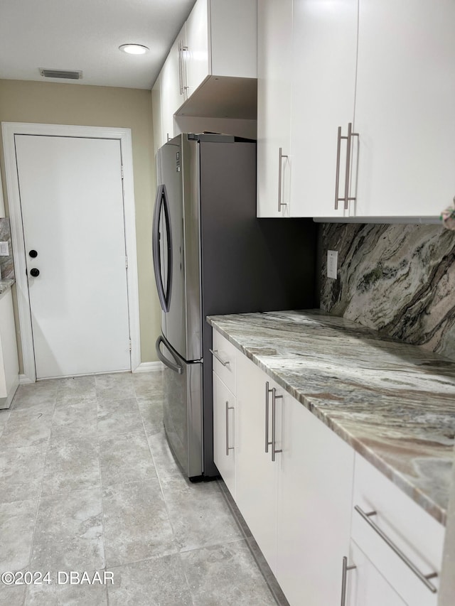 kitchen featuring white cabinets, light stone countertops, and decorative backsplash