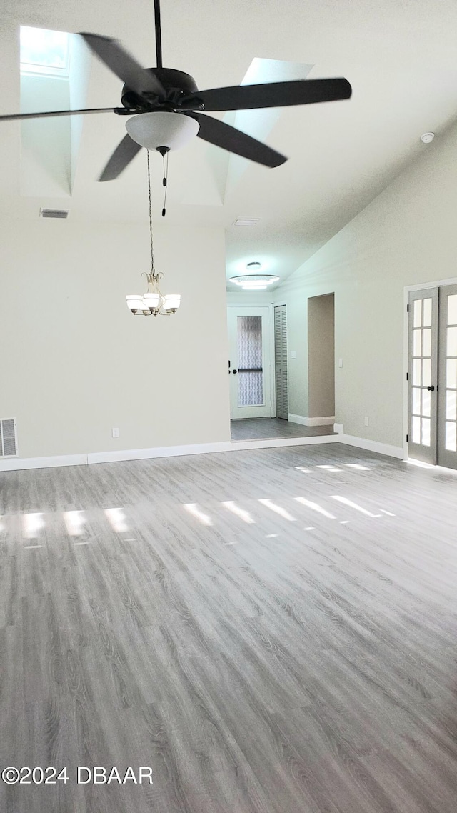 unfurnished living room with hardwood / wood-style floors, ceiling fan, french doors, and lofted ceiling